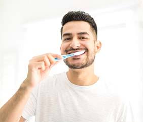 young man brushing teeth in bathroom