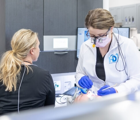 Dentist using dental tools to examine patient's teeth