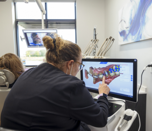 Dental team member using in office CEREC one visit dentistry milling unit connected to digital impression system